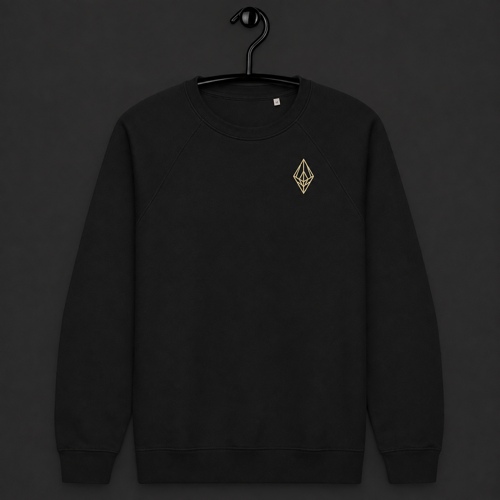 A black crewneck sweatshirt hanging on a black hanger against a dark gray background, featuring a small gold geometric diamond logo on the left chest.
